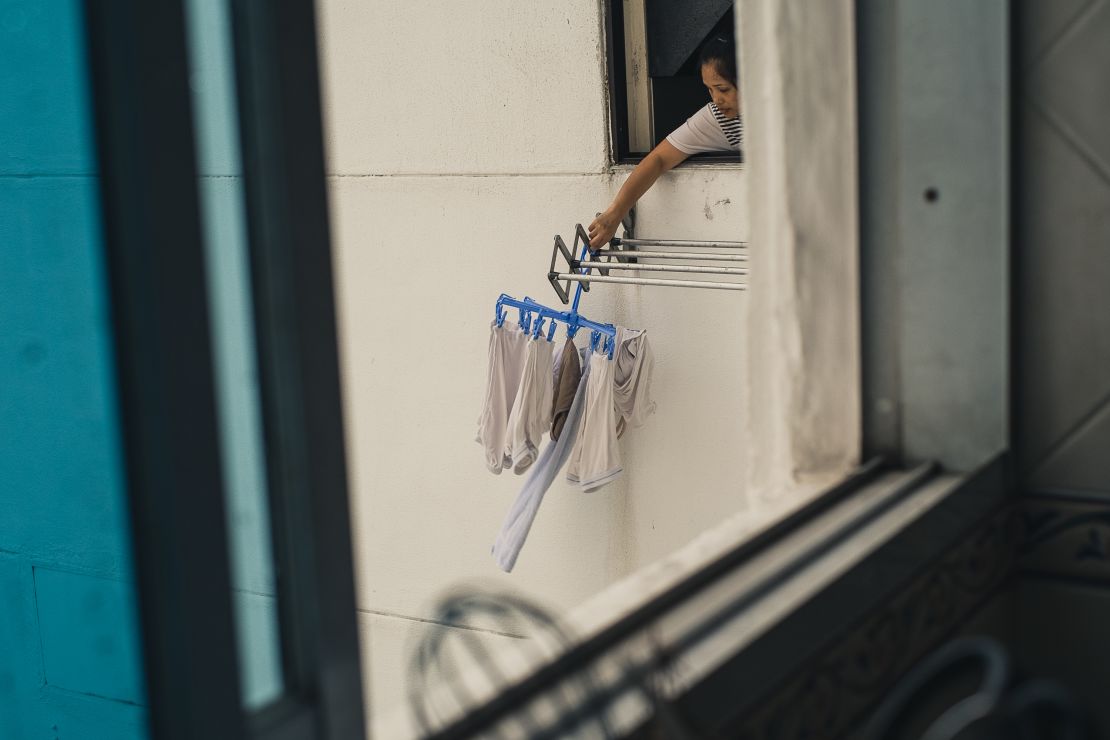 A foreign domestic worker hangs washing from the window of a condo in Singapore.