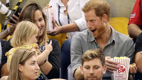 Harry sits with Hayley Henson, left, and her daughter Emily during the Invictus Games in Toronto in September. Hayley is married to British paralympian David Henson, and young Emily was sneaking bites of the prince's popcorn. Harry founded the Invictus Games, an international sporting competition for injured service members.