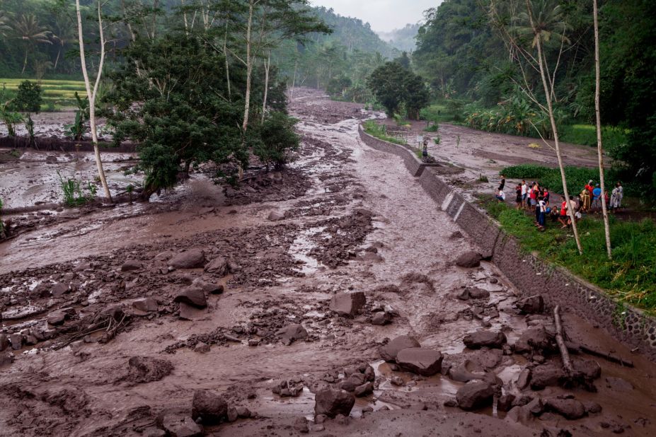 Volcanic material from the eruption flows through a local river in Gesing Villageon November 27, while villagers watch nearby ,in Karangasem, Bali, Indonesia. 