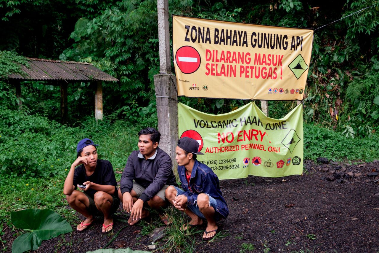 Residents at Gesing village are seen sitting in front of a sign restricting entry to the area on November 27, in Karangasem, Bali, Indonesia.