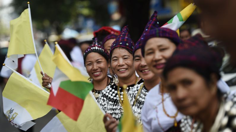 Women in traditional dress line the streets as the Pope leaves Yangon International Airport.