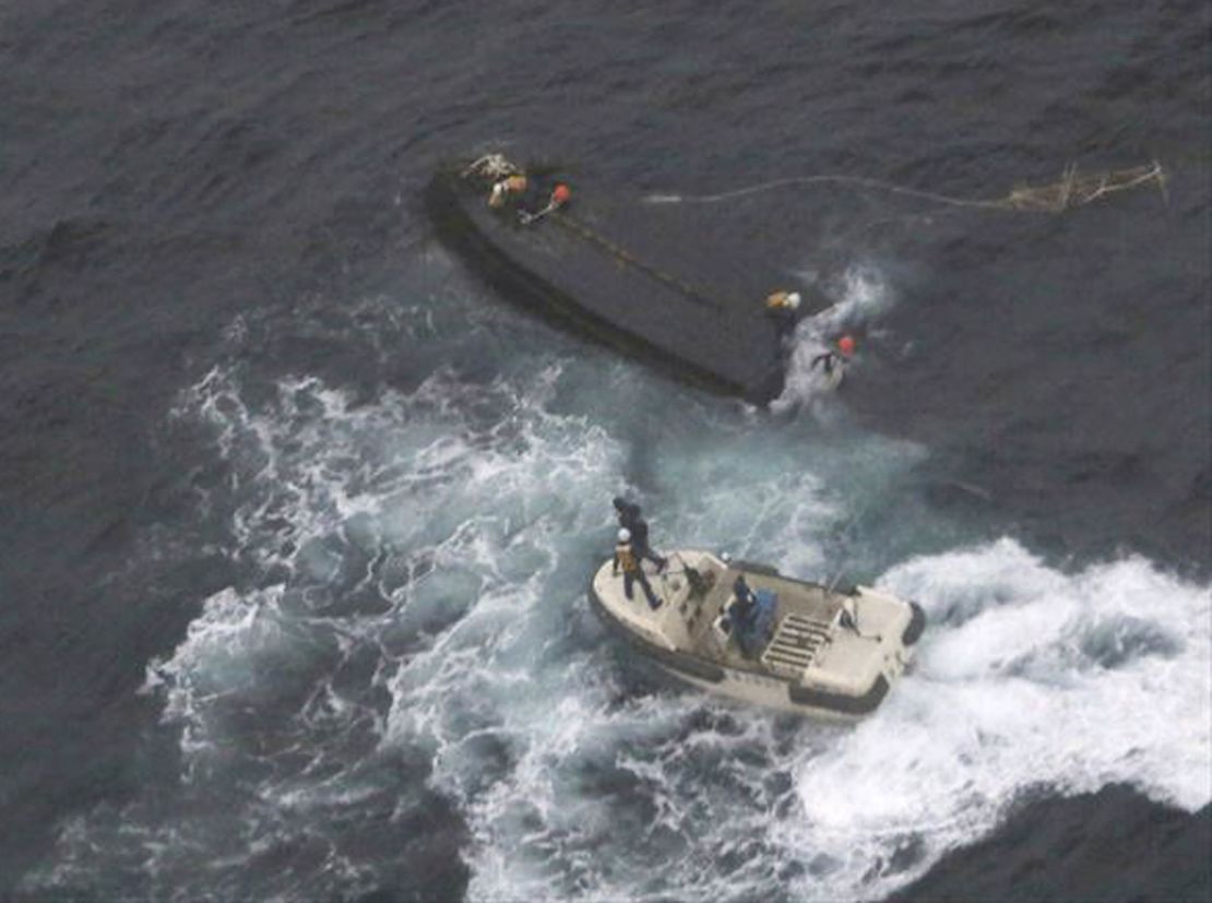 A Japan Coast Guard boat approaches a capsized wooden vessel, on Wednesday, Nov. 15, 2017. Three crew members rescued from the capsized boat are North Koreans, and Tokyo is arranging their return home. 