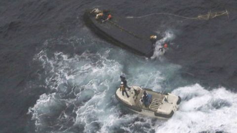 A Japan Coast Guard boat approaches a capsized wooden vessel, on Wednesday, Nov. 15, 2017. Three crew members rescued from the capsized boat are North Koreans, and Tokyo is arranging their return home. 