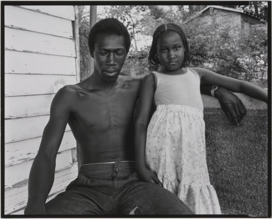 From curator Karen Haas: "During the late 1970s Boston-based photographer, Nicholas Nixon, made a groundbreaking series of portraits of southern families on the porches and front yards of their homes. Although in many cases Nixon's pictures feature large groups of people moving in and out of these semi-public spaces, this one is particularly riveting in the somewhat unexpected reversal of roles between the two figures. Here the muscular, bare-chested man, who sits with his arm draped around the child, drops his eyes and looks down, while the girl bravely meets the gaze of Nixon's view camera with a strength and self-possession that imbues the image with real emotional depth."