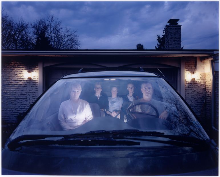 From curator Karen Haas: "Julie Mack's large-scale photograph records the young artist herself (wearing glasses) along with her parents and siblings seated in the glowing interior of the family's SUV in their Michigan driveway. At once subversively funny and totally deadpan, this minutely staged picture seems the perfect evocation of the suburban dweller's dependence on the claustrophobic environment of the family car."