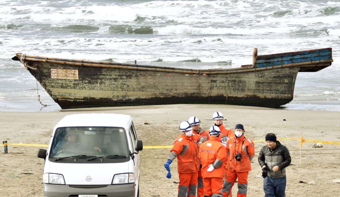 Japanese officials gather on Nov. 27, 2017, near a boat washed ashore in Oga, Akita Prefecture. Authorities found eight bodies in the unidentified wooden boat.