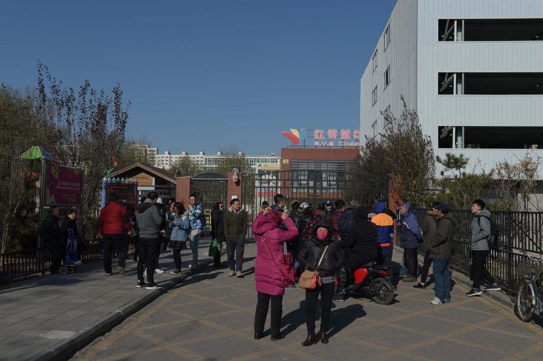 People stand in front of the main gate of the RYB Education New World kindergarten in Beijing on November 24, 2017.