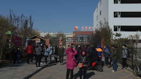 People stand in front of the main gate of the RYB Education New World kindergarten in Beijing on November 24, 2017.