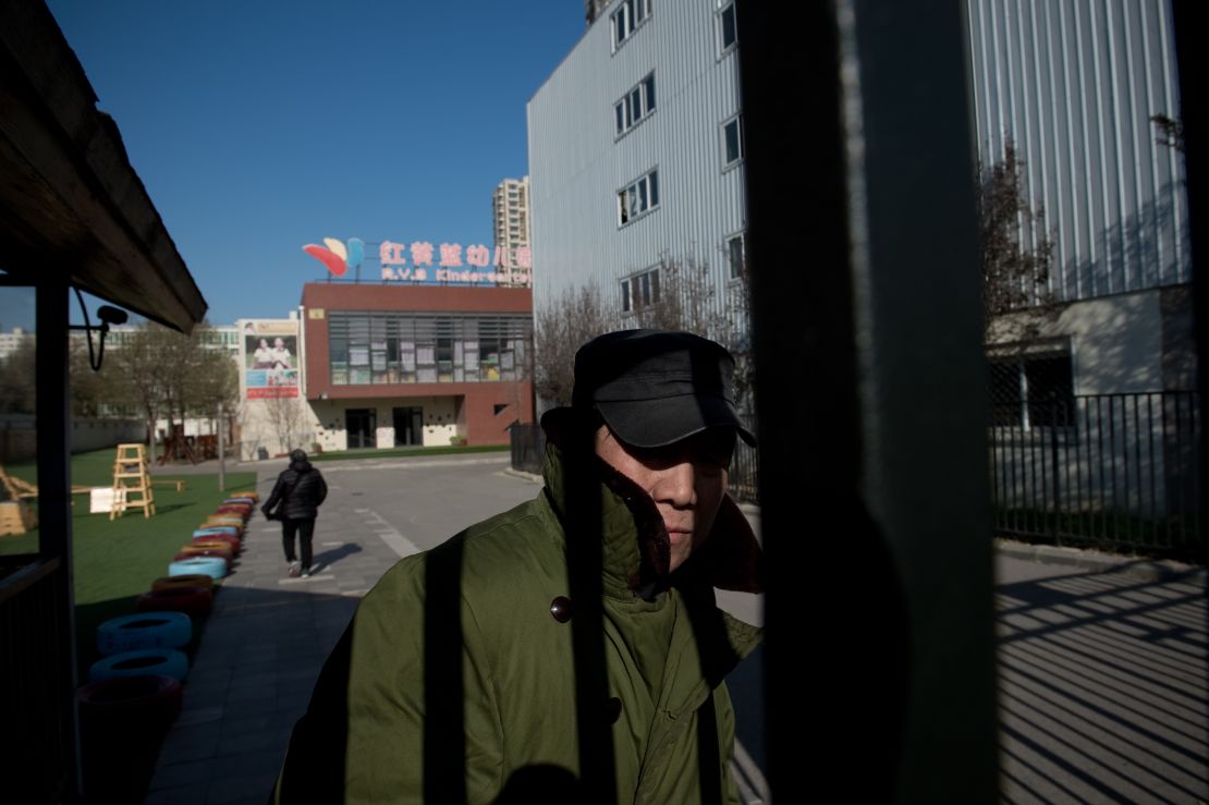 A security guard stands behind the gate of the RYB Education New World kindergarten in Beijing.