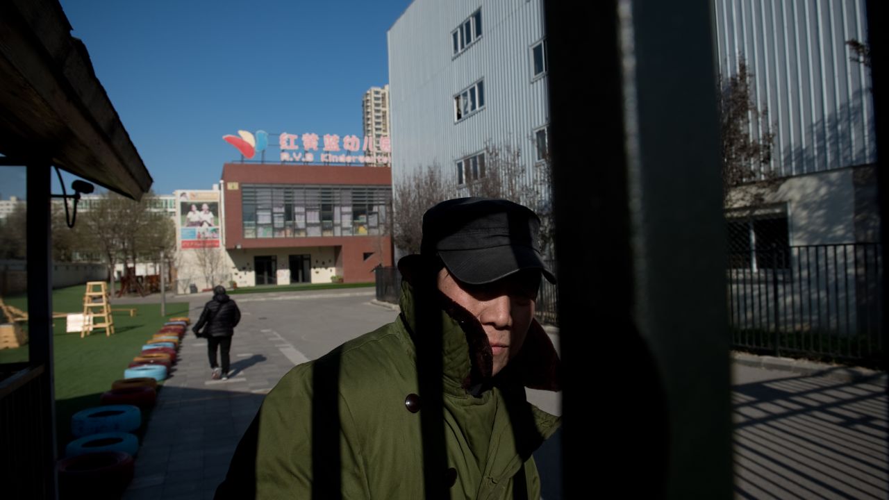 A security guard stands behind the gate of the RYB Education New World kindergarten in Beijing.