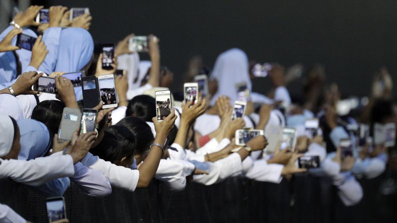Nuns hold their phones to film the Pope as he arrives for a meeting in Yangon on November 29.