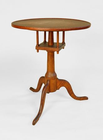 Curly maple, cherry, butternut and pine are combined in one piece (c. 1850), exemplifying Shaker craftsmanship, aesthetics and innovation. The tabletop sits on a revolving birdcage support, with a simple tapered standard standing on three cabriole legs.