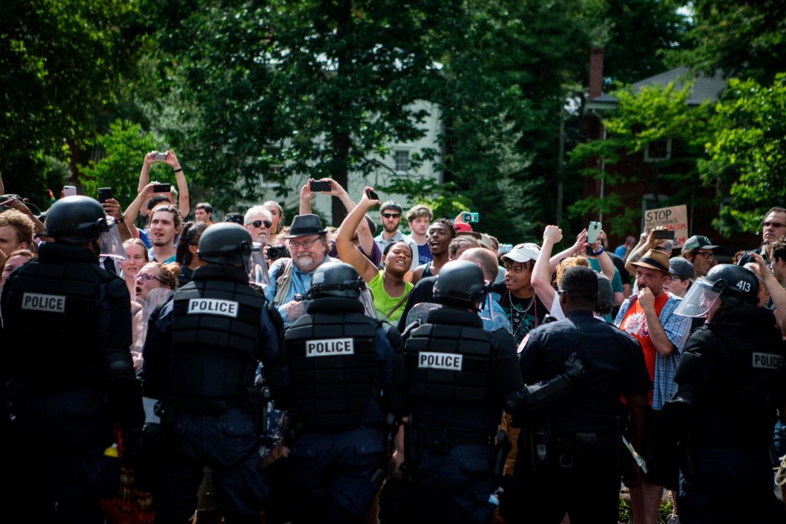 Riot police hold back counterprotesters as Ku Klux Klan members leave last year's Charlottesville rally.