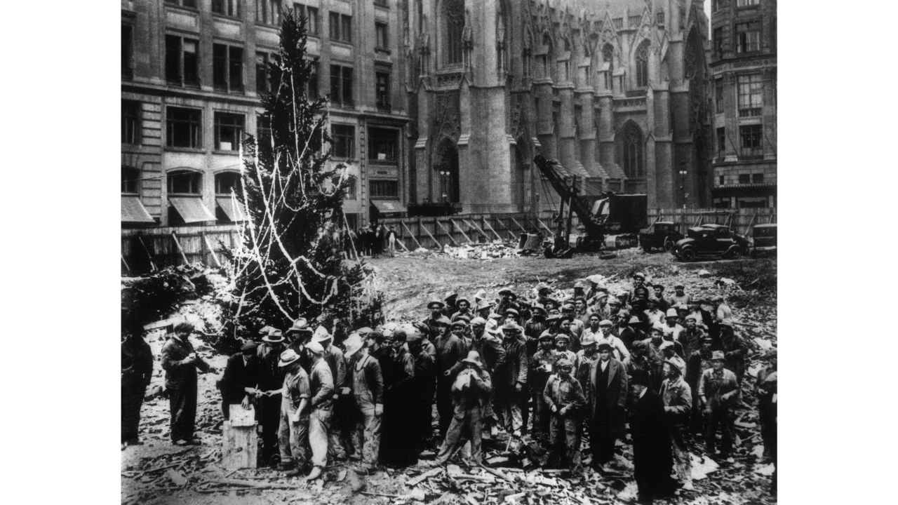 <strong>1931:</strong> Construction workers line up for pay beside the first Rockefeller Center Christmas tree in New York. The tree went on to become an annual tradition and a New York landmark. St. Patrick's Cathedral is visible in the background on Fifth Avenue. Click through the gallery for more photos of festive Rockefeller Center through the decades: 