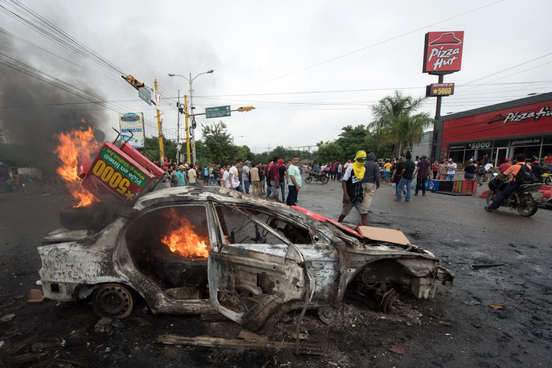 A car burns after being set on fire by supporters of Honduran presidential candidate Salvador Nasralla during post-election protests.