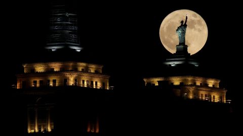 The moon rises in front of a replica of the Statue of Liberty sitting atop the Liberty Building in downtown Buffalo, N.Y.