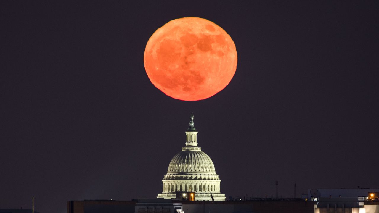 The moon rises behind the US Capitol in Washington, DC, viewed from Arlington, Virginia.