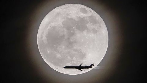 An airplane crosses in front of the moon, seen in Avondale Estates, Georgia.