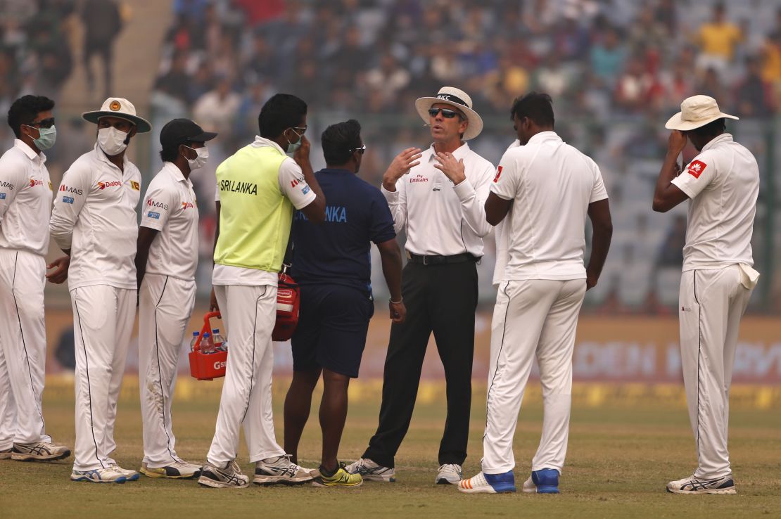 Officiating umpire Nigel Llong, third from right, addresses Sri Lanka's players wearing masks, during a brief break on Sunday's match. 