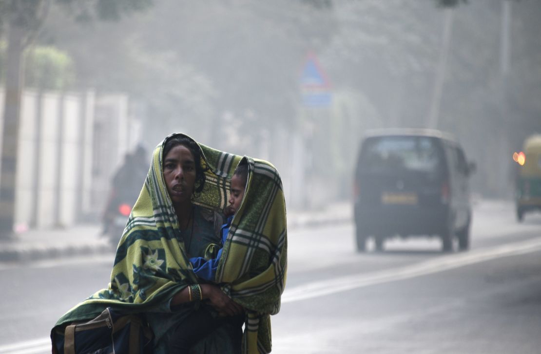 An Indian woman and her child walk amid heavy smog on a street in New Delhi on December 4, 2017.