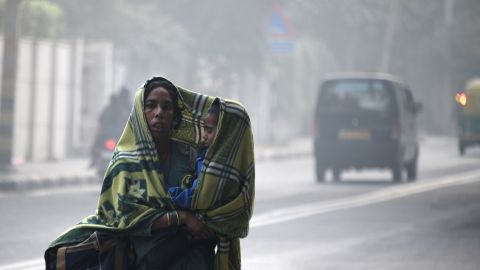 An Indian woman and her child walk amid heavy smog on a street in New Delhi on December 4, 2017.