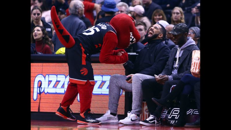 The Toronto Raptors' mascot jokes with rapper Drake during an NBA game on Friday, December 1.