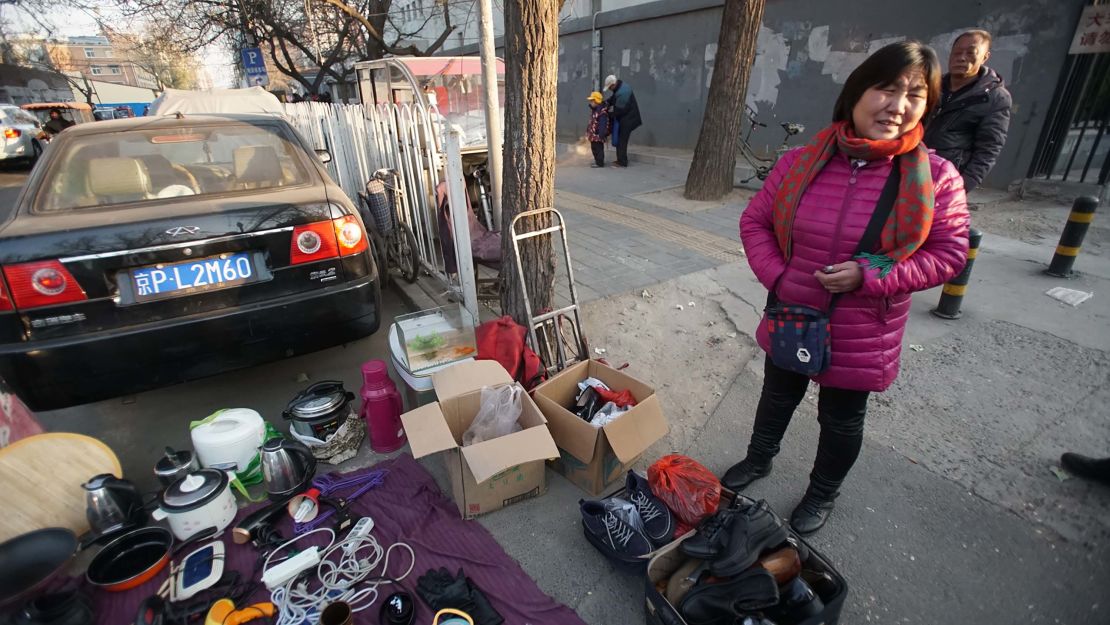 Zhao Guihua, an evicted migrant worker, sells her possessions on the street 50 meters from her old home. She said she and her husband are leaving Beijing because they can't afford a new home.