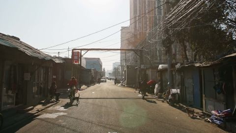 A street view of a once bustling market street after buildings on one side were demolished by authorities. Remaining stores prepare to shut down.