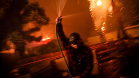 Prescott McKenzie hoses down the roof as embers move with the wind.