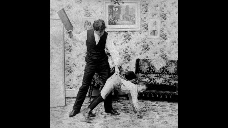 The tools of spanking are varied. In this vintage image, a man uses a paddle. For adults administering punishment,<strong> </strong>the use of switches, belt straps, paddles and the like delivered increased punishment while saving their hands from the sting of the swat. <br />In the slave trade, there was a crueler reason for the use of a paddle or strap. In his book "<a href="index.php?page=&url=https%3A%2F%2Fbooks.google.com%2Fbooks%3Fid%3DR-BAAAAAcAAJ%26printsec%3Dfrontcover%26pg%3DPA304%23v%3Donepage%26q%26f%3Dfalse" target="_blank" target="_blank">Flagellation and the Flagellants: A History of the Rod in all Countries from the Earliest Period to the Present Time</a>," the Rev. William Cooper explains that straps were used to keep from scarring slaves and reducing their value: "It is said that with this instrument a slave could be punished to within an inch of his life, and yet come out with no visible injury, and with his skin as smooth as a peeled onion."