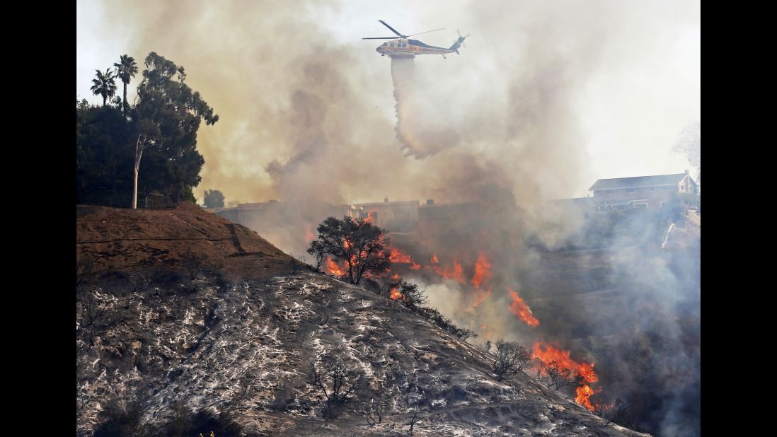 A Los Angeles County Fire Department helicopter makes a water drop on flames after the Skirball Fire swept through Bel-Air on December 6.