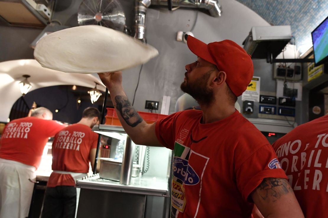 Neapolitan pizza makers prepare pizzas in a bottega.