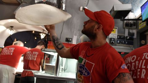 Neapolitan pizza makers prepare pizzas in a bottega.