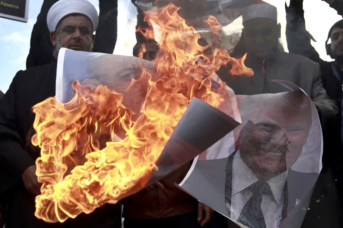 Palestinians burn posters of Israeli Prime Minister Benjamin Netanyahu and US President Donald Trump during a protest Thursday.