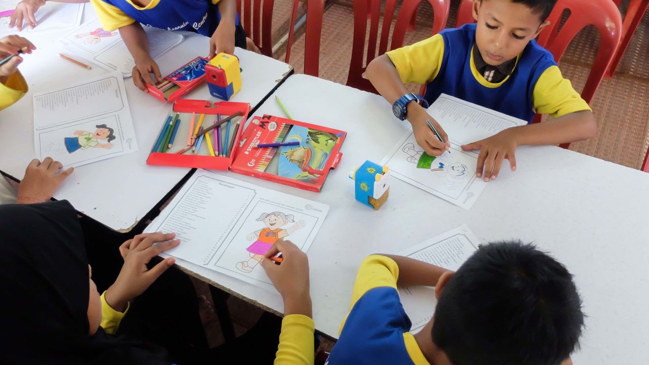 Younger students doing colouring work.