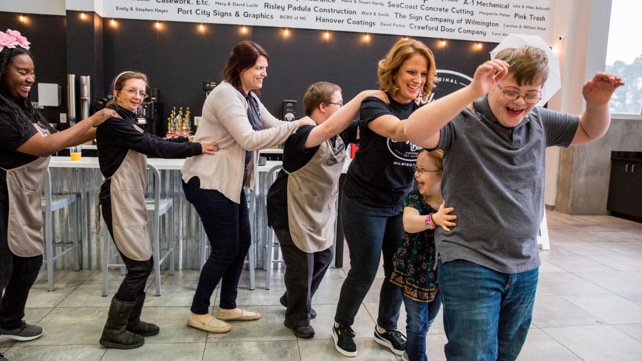 Bitty & Beau's Coffee staff members join a conga line with Wright and her daughter Bitty, 7, and son Beau, 12, during a dance break. The business is named for the children, who live with Down syndrome. She and her husband were determined to create employment opportunities for people like Bitty and Beau when they discovered that 70% of disabled people don't have jobs.