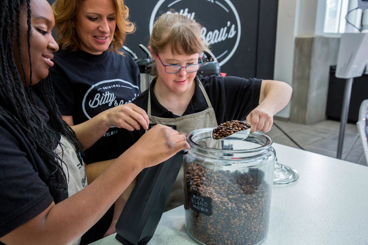 Wright helps employees Jesse Guillaume (left) and Elizabeth Johnson fill coffee bean bags at the shop on a Monday in November 2017. Bitty & Beau's Coffee is known as "The Happiest Place in Wilmington," but that's not just because of its mochas and lattes -- at the heart of this North Carolina coffee shop's popularity is its unique staff. 
