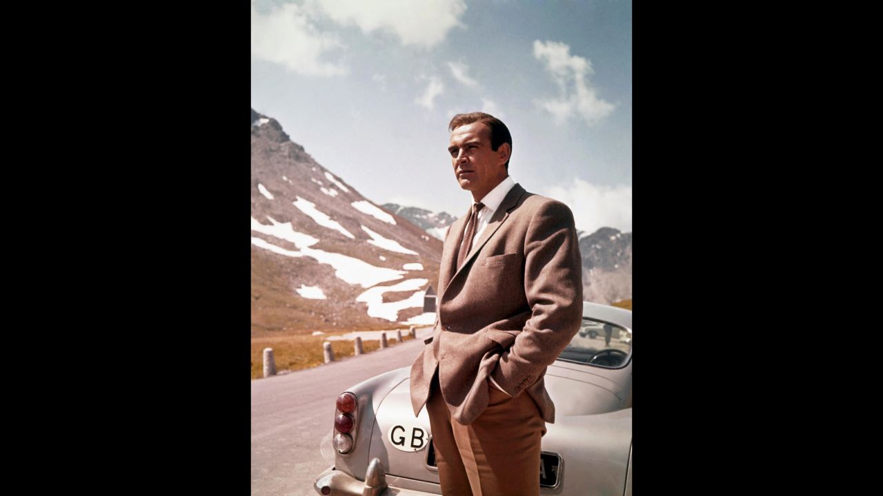 Connery poses as James Bond next to his Aston Martin DB5 in a scene from "Goldfinger" in 1964. Bond is often seen in the movies driving the car at high speed.