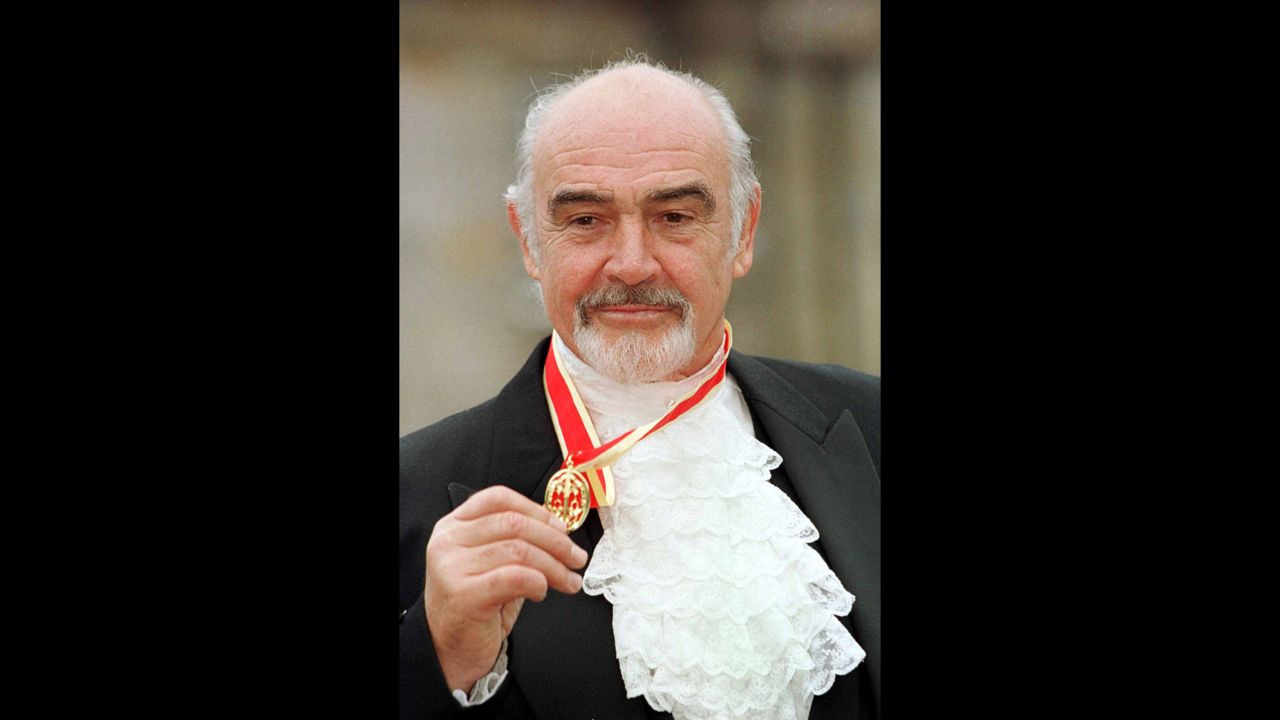Connery poses for photos in full Highland dress along with his medal after he was formally knighted by the Queen in 2000.