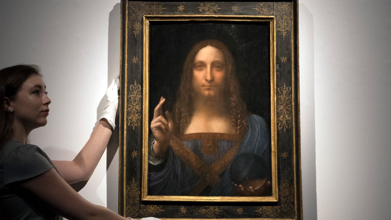 LONDON, ENGLAND - OCTOBER 24:  A member of staff poses with a painting by Leonardo da Vinci entitled 'Salvator Mundi' before it is auctioned in New York on November 15, at Christies on October 24, 2017 in London, England. The painting is the last Da Vinci in private hands and is expected to fetch around 100,000,000 USD.  (Photo by Carl Court/Getty Images)