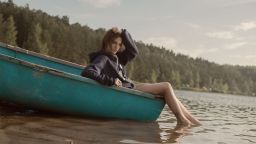 Stock image of a young woman in a boat by the river. Location unknown