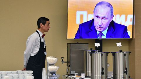 A waiter stands by a screen broadcasting Putin's marathon annual press conference in Moscow on Thursday.