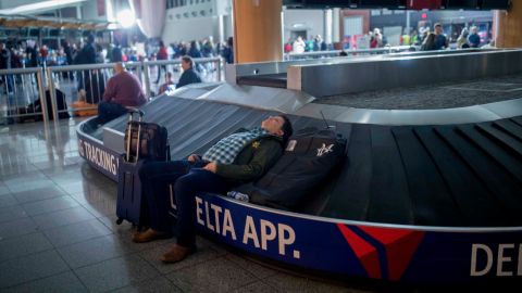 A traveler sleeps on a baggage carousel at Hartfield-Jackson Atlanta International Airport on Sunday.