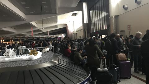 Stranded passengers congregate around baggage claim Sunday.