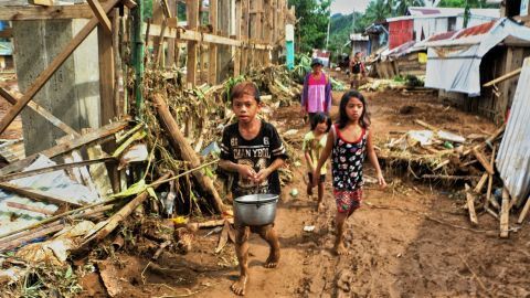 Children walk past debris and damaged houses trees in Barangay San Mateo Borongan in eastern Samar on December 17, 2017.