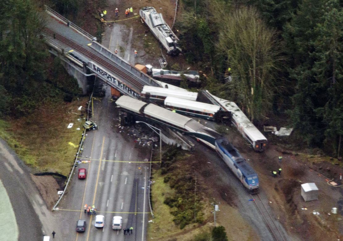 Cars from an Amtrak train that derailed above lie spilled onto Interstate 5.
