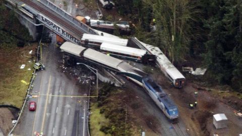 Cars from an Amtrak train that derailed above lie spilled onto Interstate 5.