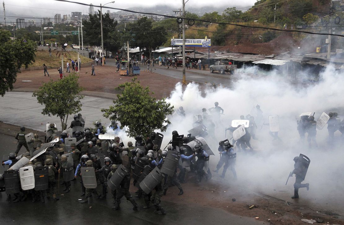 Police stand amid tear gas as they clash with supporters of opposition presidential candidate Salvador Nasralla in Tegucigalpa, Honduras, Monday, Dec. 18, 2017. 