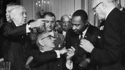 US President Lyndon B. Johnson shakes the hand of Dr. Martin Luther King Jr. (1929  - 1968) at the signing of the Civil Rights Act while officials look on, Washington DC. (Photo by Hulton Archive/Getty Images)