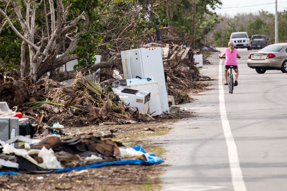 A cyclist passes the mounds of trash still littering the sides of roads in the Florida Keys.